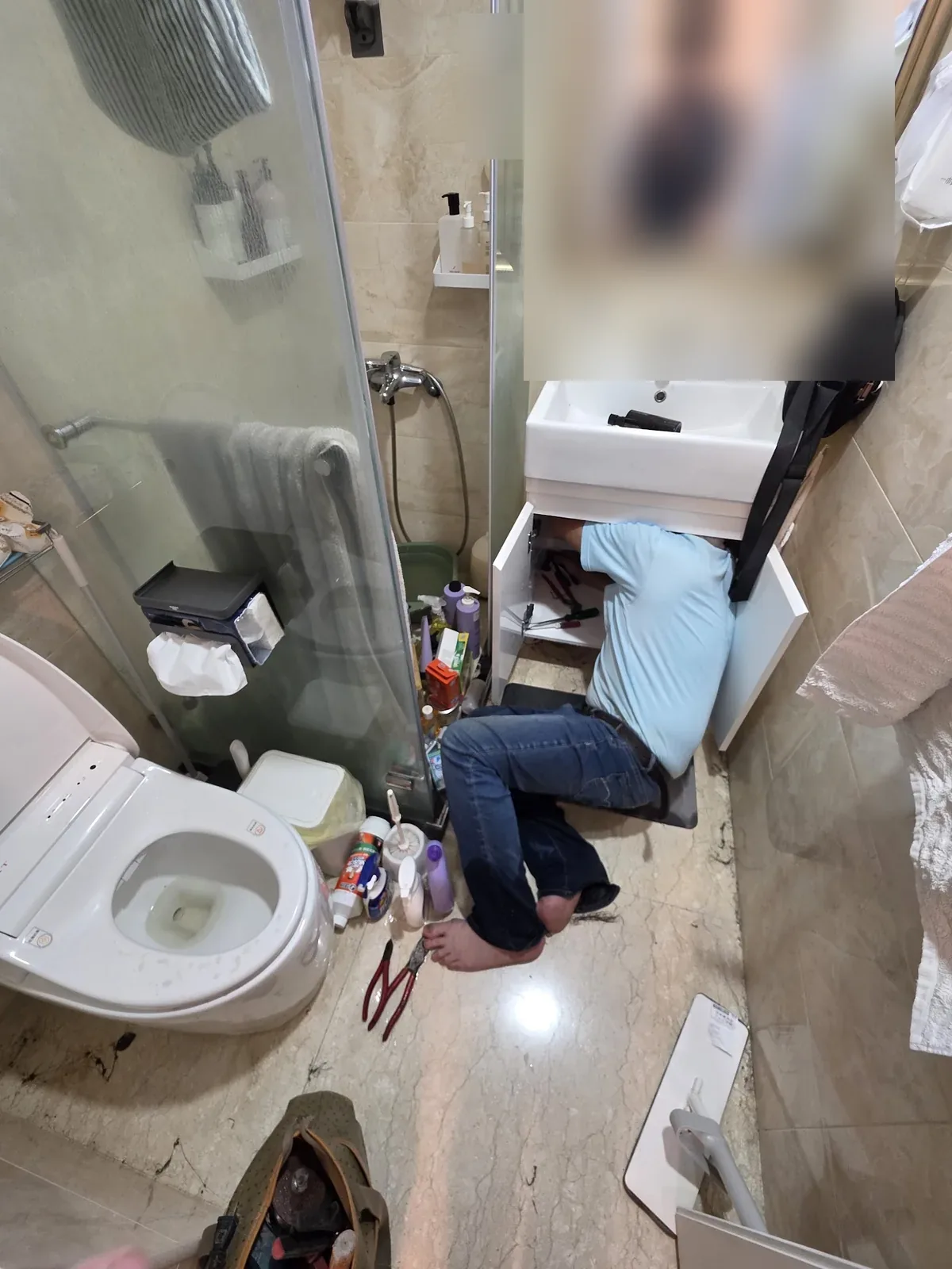 技師在浴室面盆下方檢修管路
